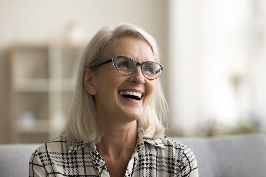 Happy older woman smiling in a home, sitting on a couch