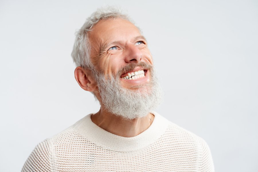 Older man smiling while looking up against an isolated white background