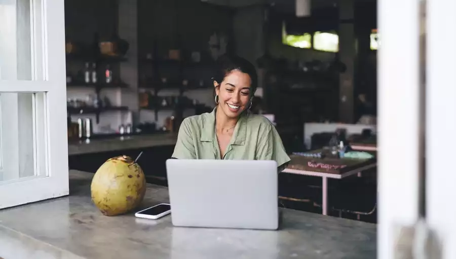 Happy, smiling woman working on her laptop in an open kitchen setting